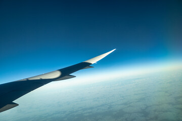 Fototapeta premium Wing of plane taking off at dawn with beautiful scenery in the background. Concept: Airplanes, holidays, travelling.