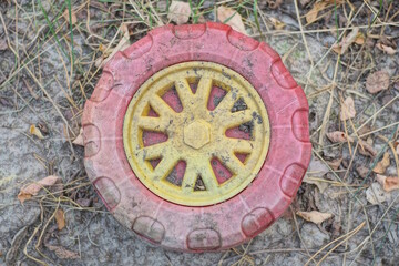 trash from plastic red yellow baby wheel lies on the street on gray earth