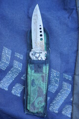 one large gray folding knife in a colored cloth case lies on a black table