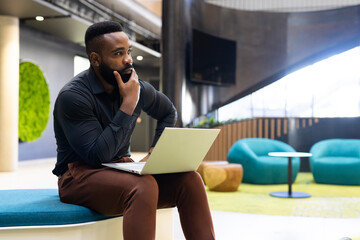 Thinking deeply, businessman with laptop sitting in modern office space, copy space