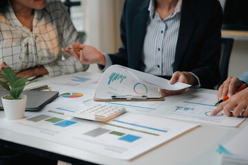 Business team reviewing financial documents with charts and graphs on a table during an office meeting