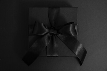 Black Friday Sale. Black gift box with ribbon bow isolated on black, top view