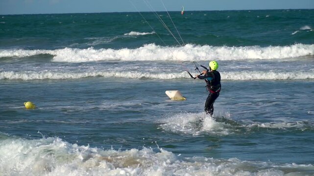 Slow motion, young sporty man kitesurfing in the sea at sunset.