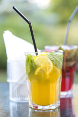 A glass of lemonade with a straw in it sits on a table next to a napkin