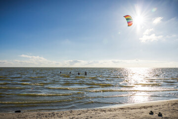 Leute im Sommer am Strand stehen im Meer in Holland und lassen einen Lenkdrachen steigen