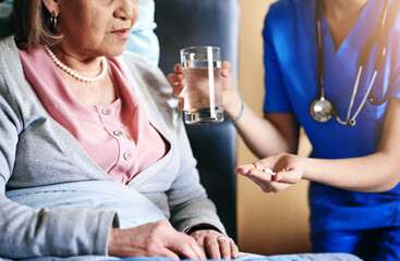 Senior, woman and nurse with medication in hands at retirement facility for healthcare or prescription drugs. Elderly, patient or caregiver in nursing home with pills assistance or water for wellness
