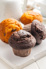 Sweet muffin cakes on cutting board on white table.