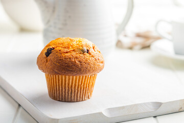 Sweet muffin cakes on cutting board on white table.