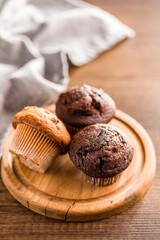 Sweet muffin cakes on cutting board on wooden table.