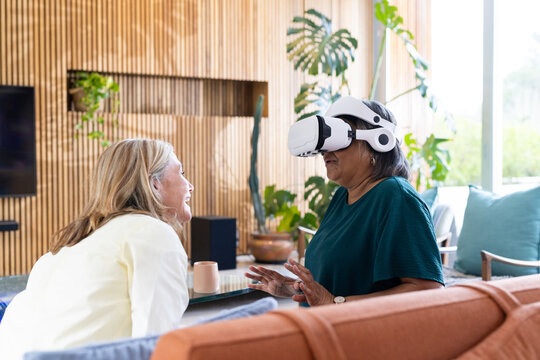 At home, using vr headset, senior woman interacting with multiracial female friend