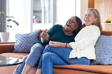 At home, Laughing together, two senior women relaxing on couch in living room