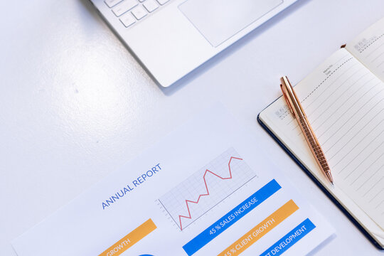 Analyzing annual report with laptop and notepad, focusing on business growth