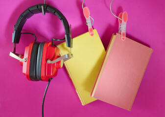audiobooks concept with  books and vintage headphones.Selective focus,bright pink background
