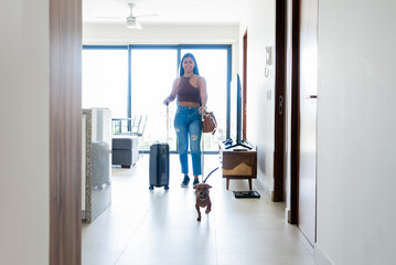 Obraz premium Mexican Woman Leaving Home with Travel Suitcase and Excited Dachshund