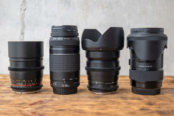 Four different camera lenses standing on a wooden surface