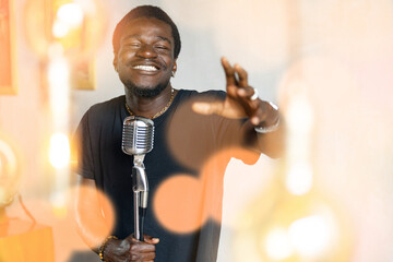 Handsome attractive african american singer, man singing in retro microphone in studio music...