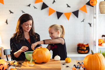 Photo Description:
A mother and her daughter smile as they carve pumpkins together for Halloween....