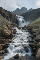 Fototapeta premium Majestic waterfall cascading down rocky cliffs in a mountainous landscape during the day