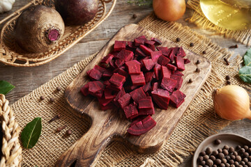 Sliced purple beet root on a cutting board with onions and spices - preparation of fermented beet...