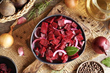 Fermented red beet kvass in a black bowl with onions, garlic and spices, top view