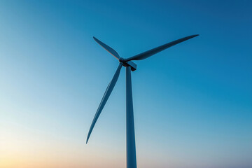 Fototapeta premium View of a wind turbine against a clear sky during sunset, showcasing renewable energy in a serene landscape