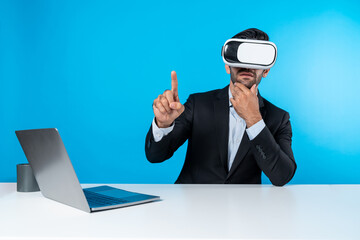Skilled business man looking at data analysis while sitting at table with laptop and wearing VR glasses. Project manager working by using virtual reality system or connecting at metaverse. Deviation.
