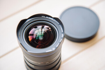 Wide angle lens resting on white wood surface with lens cap off camera