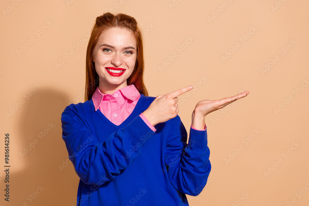 Wall mural Photo of charming attractive lady dressed blue pullover pointing fingers showing arm empty space isolated beige color background