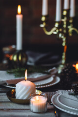 Rustic Scandinavian style zero waste eco-friendly dinner table decor for Christmas or new year family celebration. Wooden table, natural elements like pine cones, fir tree branches, candles