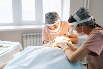 Professional two female trichologist collecting hair follicles from back of head of male patient...