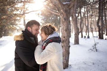 a moment of care and warmth: a man covers a woman with a cozy checkered blanket against the backdrop of a winter forest. This is a Christmas scene filled with love and the warming spirit of the holida