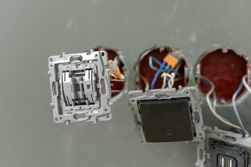 Technicians are seen installing electrical switch plates in wall openings, preparing for the wiring...