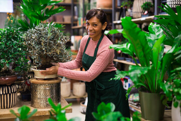 Portrait of a latino woman owner flower shop with potted plants in her hands