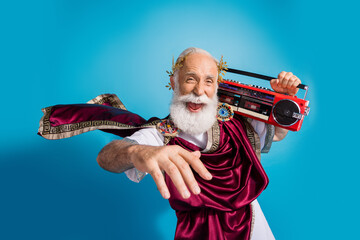 Photo of crazy cheerful man ancient greek hero wearing traditional clothes hold radio music isolated on blue color background