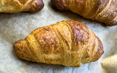Freshly Baked Golden Croissants Cooling on Parchment Paper in a Warm Kitchen