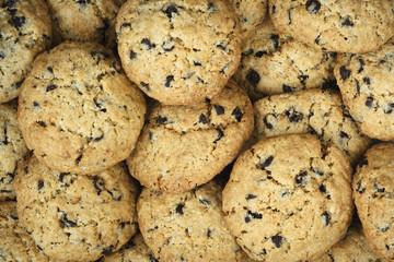 Freshly baked oatmeal chocolate chip cookies fill the frame. Background image. Top view