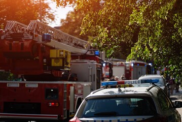 Firefighters and police respond to emergency, fire trucks with ladders and flashing blue lights....