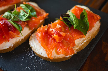 delicious juicy canapes of red fish, salmon on white bread with red tomato, on a dark background,...