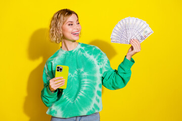 Photo of cheerful pretty lady dressed green sweatshirt winning money modern gadget empty space...