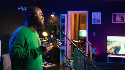 Singer performing his new track creation on a microphone, manipulates his audio files recordings...