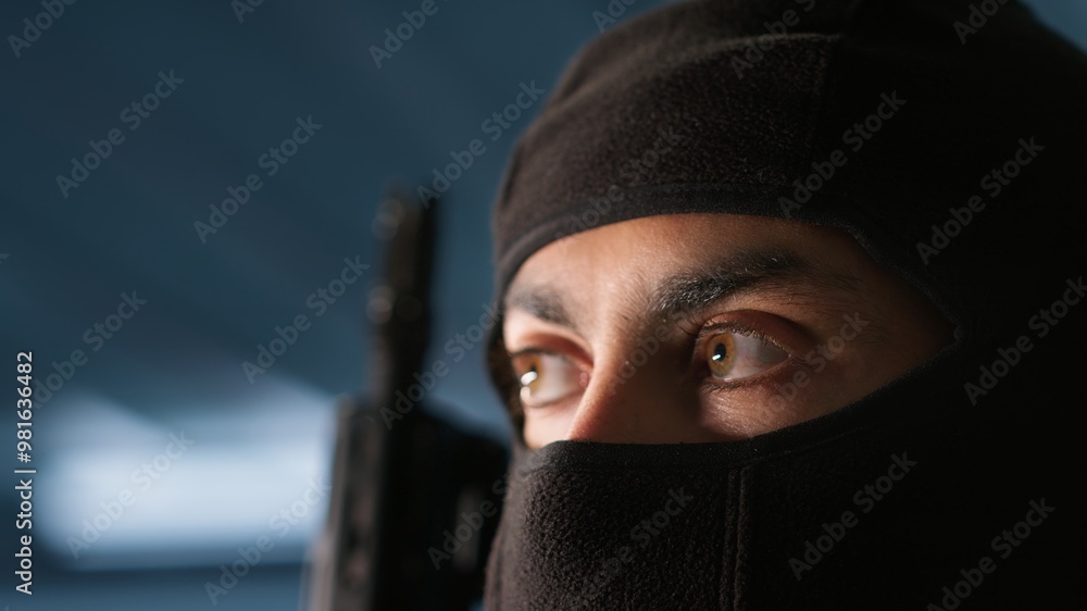 Poster terrorist hiding identity, attacking enemy command center. close up of masked insurgent inspecting r