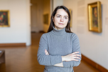Interested woman tourist visiting exhibition of antique paintings in art museum..