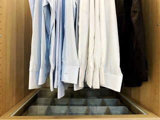 Dry-cleaning service. Many different clothes hanging on rack against white background, space for...
