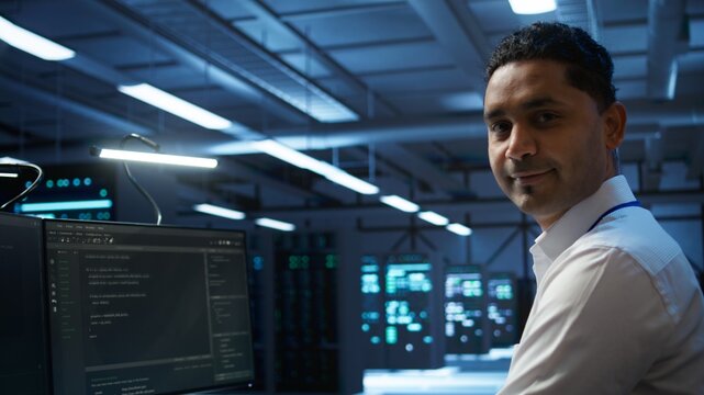 Portrait of smiling data center technician responsible for installation and repair of networking equipment solving tasks. Jolly IT expert doing maintenance on server room infrastructure, camera B