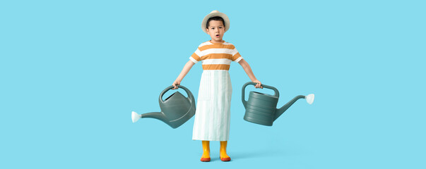 Cute little Asian boy with watering cans on blue background