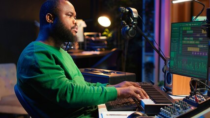 Talented artist composing new lyrics for his tracks and recording music with audio devices in his home studio. Singer composer writes melodic material by taking notes and creating rhymes or songs