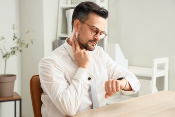 Young businessman with smartwatch checking his pulse at table in office