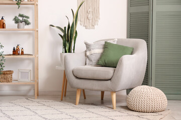 Interior of living room with green folding screen, armchair and shelf unit