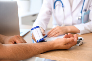 Female doctor with infrared thermometer measuring man's temperature in clinic, closeup