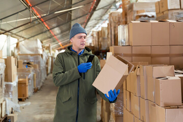 Store worker scans qr code on boxes using smartphone in warehouse
